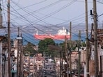 People walk trough a street, with an oil tanker ship in the background, in Matanzas, Cuba on March 30, 2026. 
