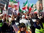 A woman holds up a sign featuring an image of Reza Pahlavi, son of the last shah of Iran, and US President Donald Trump as demonstrators march toward the White House during a rally in Washington on March 29, 2026. The event, organised by DCProtests4Iran, brought together members of the Iranian diaspora from the wider metropolitan area and surrounding states.