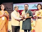 Jalgaon-based artist-turned-author Raju Baviskar (centre) won the Sahitya Akademi Award for his Marathi autobiography, Kalya Nilya Resha. (HT)