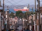 People walk trough a street, with an oil tanker ship in the background, in Matanzas, Cuba on March 30, 2026. 