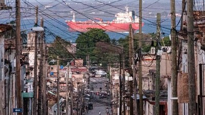 People walk trough a street, with an oil tanker ship in the background, in Matanzas, Cuba on March 30, 2026. (AFP) People walk trough a street, with an oil tanker ship in the background, in Matanzas, Cuba on March 30, 2026. (AFP)