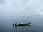 A farmer rows a boat with plant saplings amid rain, at Dal Lake in Srinagar, on Friday. (PTI)