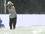 A groundsman gestures as he covers the pitch after rain stopped play during the IPL 2026 match between KKR and PBKS.
