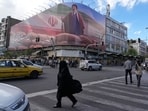 People walk past a billboard that shows a graphic depicting Iran's Supreme Leader Ayatollah Mojtaba Khamenei in downtown Tehran, Iran.