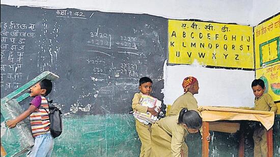 A student in a Lucknow school sweeps the classroom while others adjust the furniture. (Deepak Gupta/HT Photos)