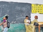 A student in a Lucknow school sweeps the classroom while others adjust the furniture. (Deepak Gupta/HT Photos)