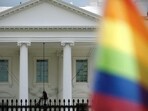 The White House is seen in the background with a LGBTQ flag in front. 