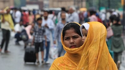 A woman covers her child with her shawl amid rain in New Delhi on Tuesday. . (ANI) A woman covers her child with her shawl amid rain in New Delhi on Tuesday. . (ANI)