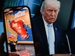 This illustration photo created in Los Angeles on April 9, 2026 shows a Lego-style AI-generated war-themed video playing on a smartphone screen in front of a photo of US President Donald Trump and US Secretary of Defense Pete Hegseth.