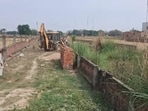 A JCB demolishes the boundary wall of plots illegally sold by land sharks as part of a demolition drive by PDA in the Bamrauli area of Prayagraj. (HT PHOTO) A JCB demolishes the boundary wall of plots illegally sold by land sharks as part of a demolition drive by PDA in the Bamrauli area of Prayagraj. (HT PHOTO)