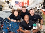 The NASA Artemis II crew, Mission Specialist Christina Koch, Mission Specialist Jeremy Hansen, Commander Reid Wiseman, and Pilot Victor Glover, pose for a group photo inside the Orion spacecraft on their way home following a flyby of the far side of the Moon.