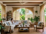 A breezy summer home setup with vetiver curtains, indoor plants, and light cotton fabrics creates a calm, naturally cool living space.