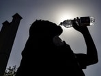 A passenger drinking water is silhouetted against the sun on a hot summer day at Jalandhar Cantonment railway station in Jalandhar. (Representational Photo by Shammi MEHRA / AFP)