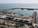 Backdropped by ships in the Strait of Hormuz, damage, according to local witnesses caused by several recent airstrikes during the U.S.-Israel military campaign, is seen on a fishing pier in the port of Qeshm island, Iran, Monday, April 13, 2026.