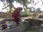 An elderly woman draws water from a well in Khinariya village of Mahoba district, where a pipeline has been laid under the Har Ghar Jal scheme but water supply has yet to begin (HT Photo)