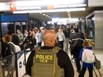 An ICE agent stands alongside a long line of travelers waiting to pass through a TSA Checkpoint at the Philadelphia International Airport on March 28. (Representational) An ICE agent stands alongside a long line of travelers waiting to pass through a TSA Checkpoint at the Philadelphia International Airport on March 28. (Representational)
