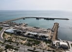 Backdropped by ships in the Strait of Hormuz, damage, according to local witnesses caused by several recent airstrikes during the U.S.-Israel military campaign, is seen on a fishing pier in the port of Qeshm island, Iran, 