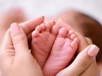 Mother holding tiny foot of newborn baby (Getty Images/iStockphoto)