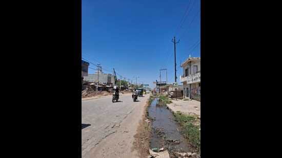 An open drain running along the road remains uncovered at several points and continues to pose a risk to commuters. (HT Photo)