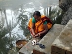 A woman prepares fish for lunch at the pond in front of her house in Kumrokhali, West Bengal. (Shutterstock)