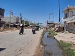 An open drain running along the road remains uncovered at several points and continues to pose a risk to commuters. (HT Photo)