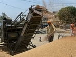 Workers separate grains of wheat from the husk at a wholesale grain market in Amritsar. (AFP)