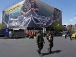 FILE - Two police officers walk in front of an anti-U.S. billboard depicting American aircraft being caught by Iranian armed forces in a fishing net beneath the words in Farsi, "The Strait of Hormuz will remain closed, The entire Persian Gulf is our hunting ground," in Tehran, Iran, Sunday, April 5, 2026. (AP Photo/Vahid Salemi, File)