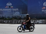 A commuter rides past a billboard for the US-Iran peace talks in Islamabad on April 13, 2026, a day after Iran and the United States failed to reach an agreement to end the war in West Asia.
