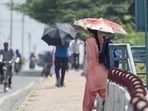 People shielding themselves with umbrella amid the hot weather conditions in Delhi (RAJ K RAJ /HT PHOTO)