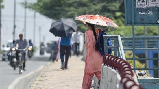 People shielding themselves with umbrella amid the hot weather conditions in Delhi (RAJ K RAJ /HT PHOTO)