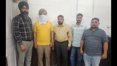SHO Gurjeet Singh (face covered) in the custody of vigilance bureau in Ludhiana on Tuesday. (HT Photo)