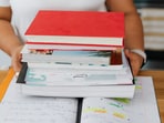 A neat stack of exam prep books, highlighted pages, and notes spread across a desk sets the tone for focused, goal-driven study. 