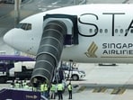 Airport officials gather near the aircraft ladder attached to the Singapore Airlines aircraft for flight SQ321 parked on the tarmac after an emergency landing at Suvarnabhumi International Airport.