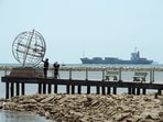FILE PHOTO: A container ship enters the Singapore Strait for the Strait of Malacca, as tourists stand at mainland Asia's southern most point in Johor, Malaysia November 12, 2016.