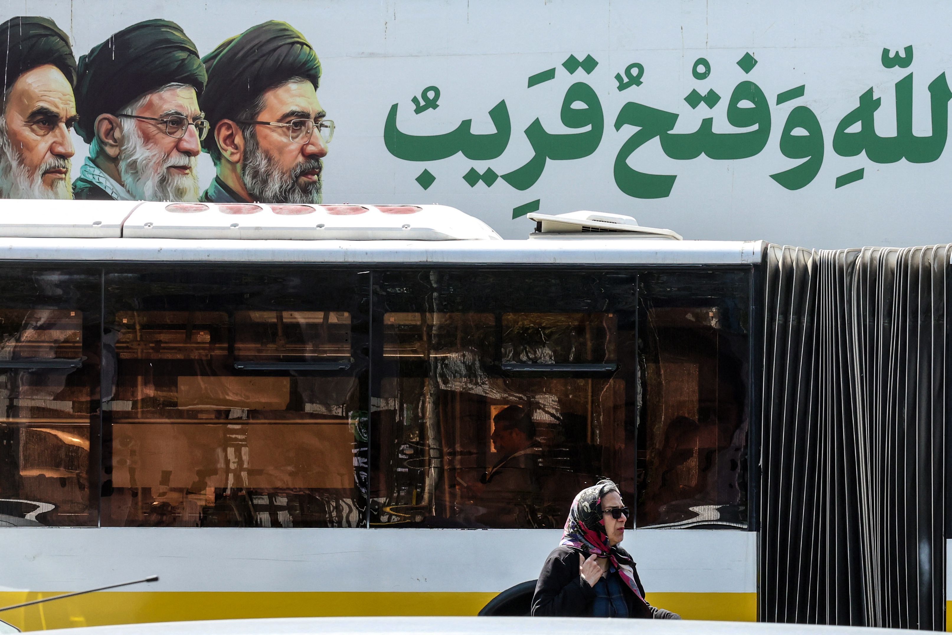 An Iranian woman walks past a bus under a banner featuring Iran's late supreme leaders Ayatollah Ruhollah Khomeini (L) and Ayatollah Ali Khamenei (C) next to newly elected supreme leader Mojtaba Khamenei, in northern Tehran on April 16 (AFP) An Iranian woman walks past a bus under a banner featuring Iran's late supreme leaders Ayatollah Ruhollah Khomeini (L) and Ayatollah Ali Khamenei (C) next to newly elected supreme leader Mojtaba Khamenei, in northern Tehran on April 16 (AFP)