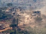 This photograph taken from the northern Israel shows Israeli tanks and military vehicles driving along the road between destroyed houses in southern Lebanon near the border with Israel. 