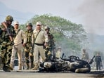 Security personnel inspect a burnt motorcycle following tension in the Kanglatongbi area of Imphal West district of Manipur, Thursday, April 23, 2026.