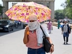 Commuters cover their heads with scarves and umbrellas to protect themselves from the scorching heat in Sector 18.