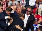 Donald Trump is seen with blood on his face, surrounded by Secret Service agents, as he is taken off the stage at a campaign event at Butler Farm Show Inc. in Butler, Pennsylvania, in 2024.