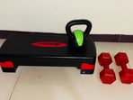 A compact home setup with dumbbells, kettlebells, and a stepper makes full-body workouts easy and enjoyable.