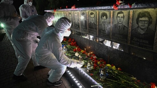 Participants dressed in white hazmat suits, representing liquidators, place candles in front of a memorial for Chernobyl victims, during a commemoration ceremony marking the 40th anniversary of the explosion at the Chernobyl nuclear power plant (AFP)