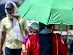 A woman protects herself and her child from the scorching heat, in Prayagraj, on Monday. (PTI Photo)