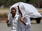 Visitors drape cloth over themselves to shield from the heat on a hot summer day visit to the Red Fort in the old quarters of Delhi on April 26, 2026. 