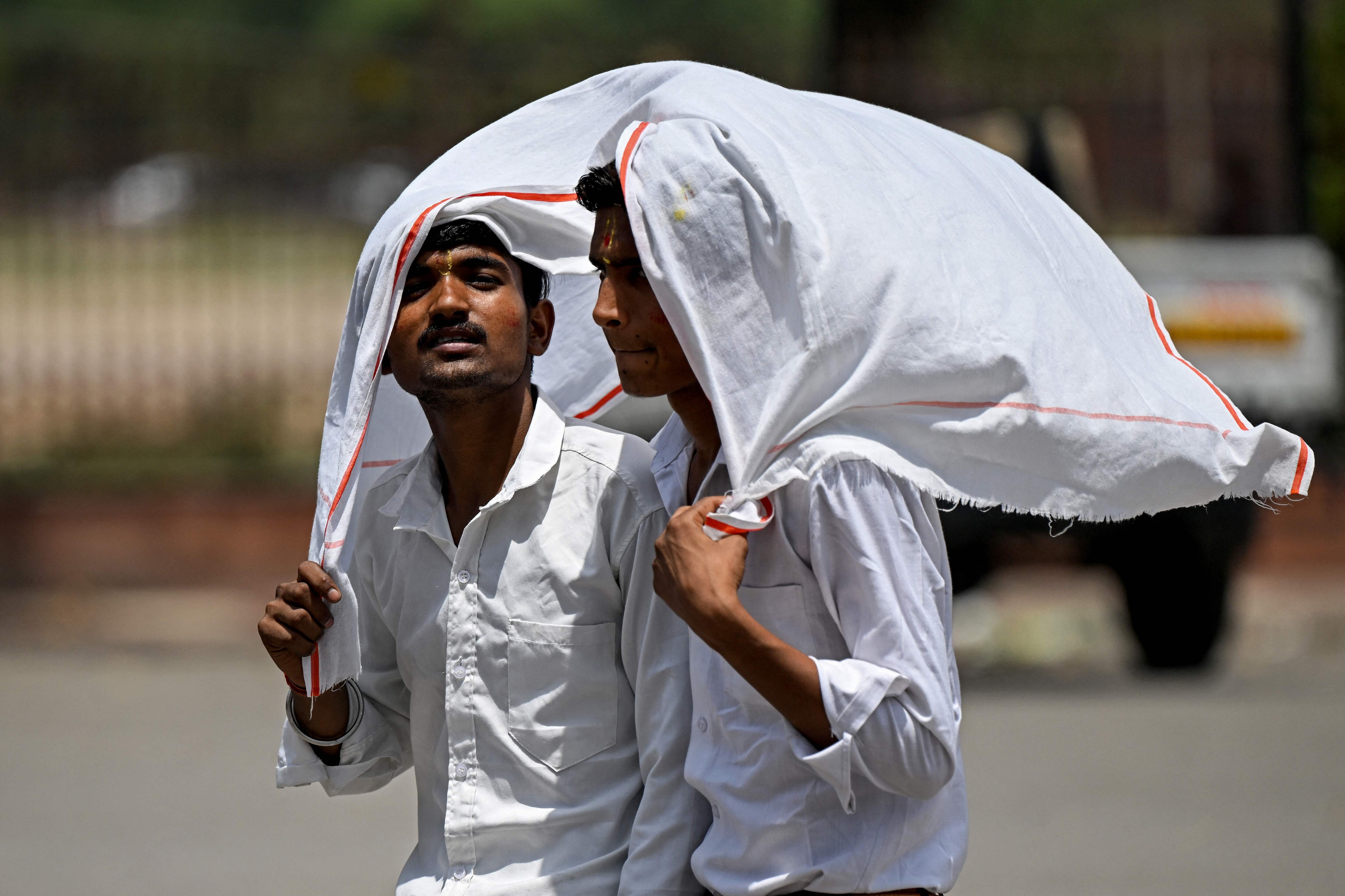 People drape cloth over themselves to shield from the heat. (AFP) People drape cloth over themselves to shield from the heat. (AFP)