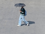 People seen covering their head and face with cloth to protect themselves from heat wave on a hot summer day at a road near Police Line, in Gurugram on Monday. (Parveen Kumar/HT)