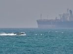 FILE - A boat sails past a tanker anchored on the Strait of Hormuz off the coast Qeshm island, Iran, April 18, 2026.
