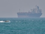 FILE - A boat sails past a tanker anchored on the Strait of Hormuz off the coast Qeshm island, Iran, April 18, 2026.