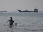 A man stands in the water, appearing to fish, as bulk carriers, cargo ships, and service vessels line the horizon in the Strait of Hormuz off Bandar Abbas, Iran, Monday, April 27, 2026.(Photo for representation)