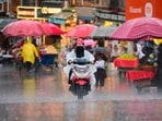 A woman drives through a market during rainfall in Srinagar, on Monday. (AP)