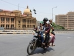 Boys wear caps to shield themselves from the sun as they ride with family on a motorbike amid hot and humid weather, near the Karachi Port Trust building, in Karachi, Pakistan, May 3, 2026. 